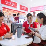 Khách hàng và nhân viên Viettel áo đỏ đang dùng điện thoại đen tại cửa hàng Viettel.
