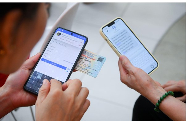 Hai người dùng điện thoại đen, kem cùng căn cước công dân xanh xác thực thông tin.