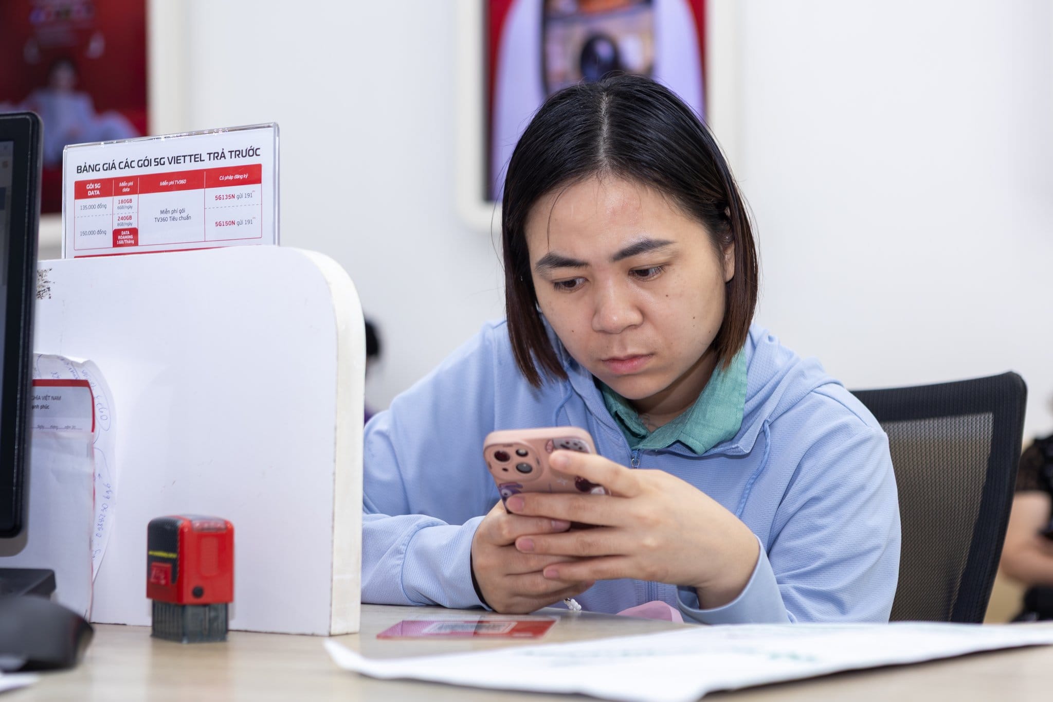 Người dùng thao tác trên điện thoại tại khu vực giao dịch Viettel. Ảnh: Viettel